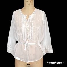 "This Edwardian blouse has such dainty detailed openwork on the front and the back! Tiny baby buttons down the front to just below the ruffles and openwork, and a drawstring waist in the back to tie over the longer front, giving a fuller front bodice. Dainty lace detailing. Handwashed and air-dried. Only issue to note is a small section of the lace edging the right sleeve is torn (pictured). Labeled \"A Larrymade Waist\" and sized a 36. Shown on a 32-24-33 form. Measurements are taken outside of Bohemian Broderie Anglaise Blouse For Daywear, Bohemian Broderie Anglaise Tops For Daywear, White Vintage Peasant Top For Spring, Victorian Spring Daywear Blouse, Victorian Lace Trim Top For Daywear, Spring Victorian Blouse For Daywear, Vintage White Tops With Lace Trim For Daywear, Peasant Tops With Lace Trim For Daywear, White Fitted Peasant Top For Daywear