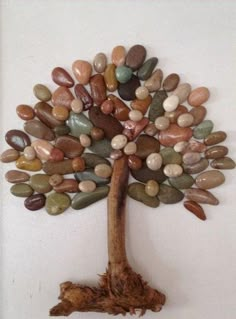 a tree made out of rocks is hanging on the side of a wall in front of a white background