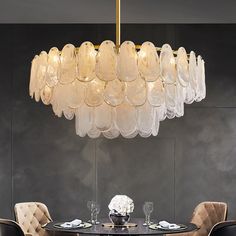 a chandelier hanging over a dining room table with chairs and plates on it