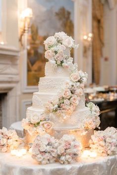 a wedding cake sitting on top of a table covered in pink and white flowers next to candles