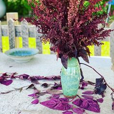 a vase filled with purple flowers sitting on top of a table next to a plate