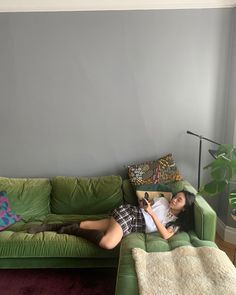 a woman laying on top of a green couch