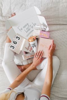 a woman laying on top of a bed holding a book