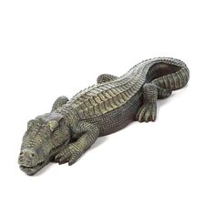 an alligator figurine is laying down on the white ground with it's mouth open