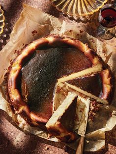 a chocolate cake with slices cut out on top of it next to some wine glasses