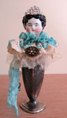 a doll is sitting on top of a vase