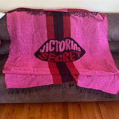 a couch covered in a pink and black victoria secret blanket with the words victoria secret on it