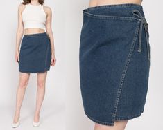 Vintage 90s a-line denim mini skirt with a wrap cut, an inside button for closure and tie at the side of the waist. It is meant to fit low on the waist, so the hem will hit just a bit above the knee. Measurements and Condition: Fits like: Labeled size 0, women's extra small Fabric: Cotton denim Brand: American Eagle, made in USA Condition: Very good, with a 1" extremely faint brown spot on the right side about halfway down (barely noticeable) Length: 17.5" Waist: 28" Hips: approximately 37" Show Mini Skirt Vintage, Jean Vintage, Wrap Mini Skirt, 90s Denim, Skirt Vintage, Denim Branding, Denim Mini, Denim Mini Skirt, Blue Jean