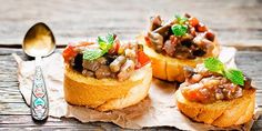 three pieces of bread topped with meat and veggies on top of a piece of parchment paper