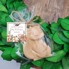 a soap bar wrapped in plastic sitting on top of green leaves next to a greeting card