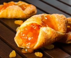 two pastries on a wooden table with jelly filling the middle one is half eaten