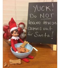 an elf is sitting next to a bowl of cookies and a sign that says yuck do not leave these cookies out for santa