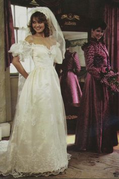 a woman in a wedding dress standing next to another woman wearing a bridal gown