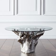 a glass table sitting on top of a wooden floor next to a white wall in an empty room