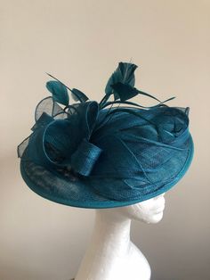 A striking teal green coloured fascinator, composed of a circular teal Sinamay base adorned with loops of vibrant teal Sinamay and finished with hand shaped feathers in the same glamorous shade. A striking addition to any formal outfit. Fascinator measuring approx 30cm in diameter. Please note as our fascinators are hand dyed to order if you feel this colour may not be quite right please request to see a colour chart. If you would like the fascinator created in an alternative dye colour which we don't currently stock there will be a charge of £30 to cover the cost of the dye and the labour.   Our timeless pieces are perfect for any special occasion from Weddings to The Kentucky Derby and Summer Garden Parties! We offer ready to wear pieces in a variety of styles and colour! However if you Elegant Turquoise Headpiece For Wedding, Elegant Turquoise Wedding Headpiece, Elegant Turquoise Fascinator For Races, Elegant Turquoise Fascinator For Kentucky Derby, Spring Turquoise Headpiece For Parties, Elegant Turquoise Fascinator For Wedding, Turquoise Fascinator For Spring Party, Turquoise Headpiece For Kentucky Derby Races, Elegant Turquoise Fascinator For Royal Ascot