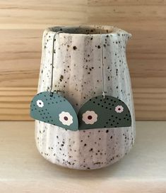 a vase with two birds hanging from it's sides