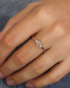 a woman's hand with a diamond ring on her left hand and the other hand holding it