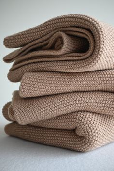 folded beige knitted blankets stacked on top of each other