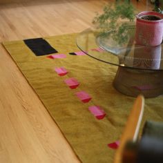 a glass table sitting on top of a wooden floor next to a vase filled with flowers