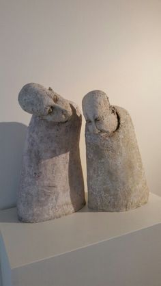 two stone sculptures sitting on top of a white shelf