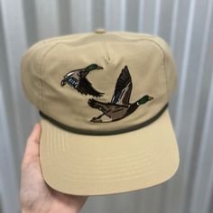 Made for the hunting enthusiast, our Ensenada Rope Hat - Wildlife - Ducks is crafted from 100% ripstop polyester and features an adjustable snap closure for the perfect fit. This hat is lightweight and durable, making it the perfect accessory to your morning duck blind adventures. 100% Ripstop Polyester Custom Pointer Design Adjustable Snap Closure Unisex Sizing Adjustable Khaki Hat For Hiking, Casual Adjustable Hat Bands For Hunting, Adjustable Khaki Hiking Hats, Khaki 5-panel Baseball Cap For Outdoor, Outdoor Khaki Trucker Hat With Curved Brim, Casual Hunting Hat With Flat Brim, 5-panel Khaki Hat For Outdoor, Khaki Trucker Hat With Curved Brim For Outdoor, Casual Flat Brim Hunting Hat