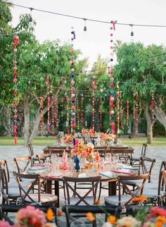 an outdoor dining area with tables, chairs and flowers on the table is surrounded by greenery