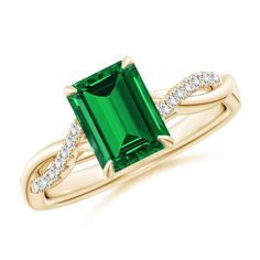 an emerald and diamond ring set in yellow gold with diamonds on the band, setting on a white background