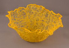 a yellow bowl that is sitting on a gray surface with some sort of yarn in it