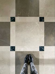 a person standing in front of a tiled floor with black and white squares on it