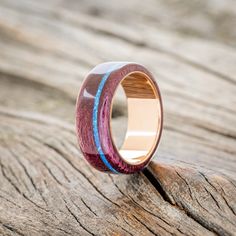 a wooden ring with blue and red inlays sitting on a piece of wood