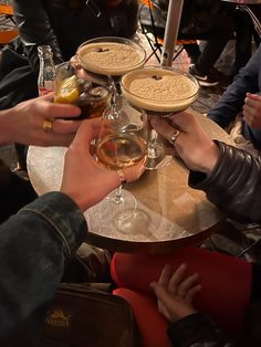 several people are sitting at a table with wine glasses and pies on top of them