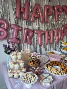 a table filled with lots of desserts and balloons that say happy birthday on it