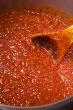 a wooden spoon stirring red sauce in a pot