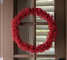 a red wreath is hanging on the front door