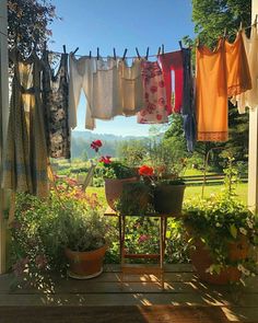 clothes hanging out to dry in the sun on an outdoor porch with potted plants