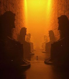 an image of some statues in the middle of a tunnel with light coming from behind them