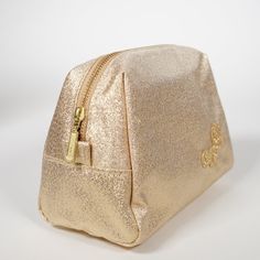 the gold cosmetic bag is on display against a white background and it's zippered open