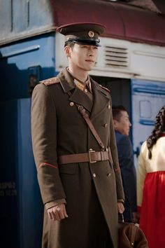 a man in uniform standing next to a train