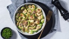 a bowl filled with brussel sprouts next to a fork and knife