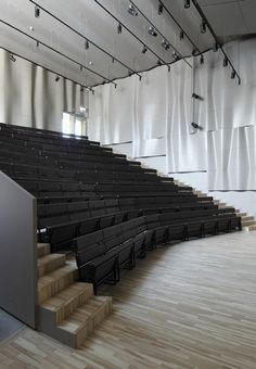 an empty auditorium with wooden floors and black seats