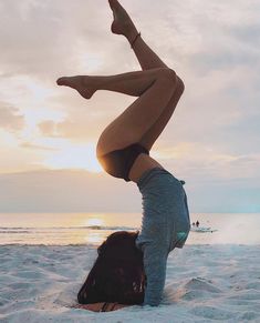 a woman doing a handstand on the beach