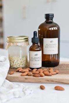 some almonds are sitting on a cutting board next to two bottles and a jar