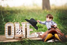 a little boy sitting on top of a wooden sign