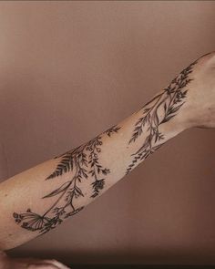 a woman's arm with flowers and leaves tattooed on the left side of her arm