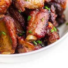 a bowl filled with cooked meat and garnished with green onions