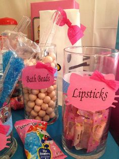 some candy and candies are sitting on a blue table with pink signs that say bath beads