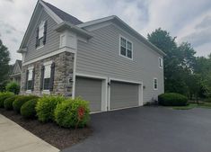 a two story house with garage and landscaping in the foreground, on a cloudy day