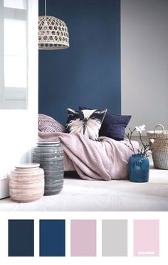 a bedroom with blue walls and white bedding, pillows and blankets on the floor