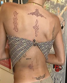 a woman with tattoos on her back standing in front of a mirror