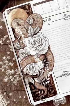 an open notebook with a snake and roses on it